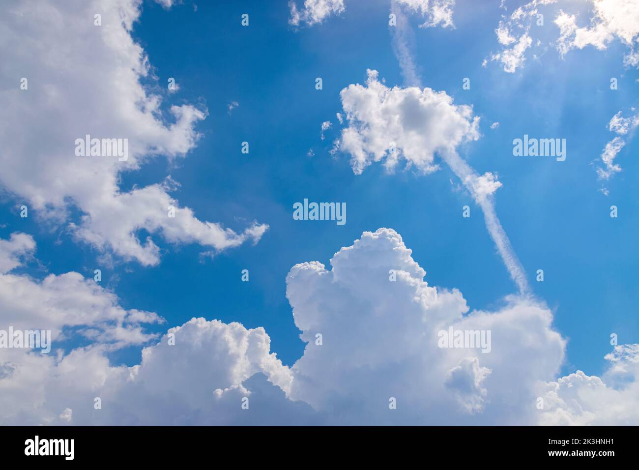 Engine exhaust contrails in the blue cloudy sky. Stock Photo
