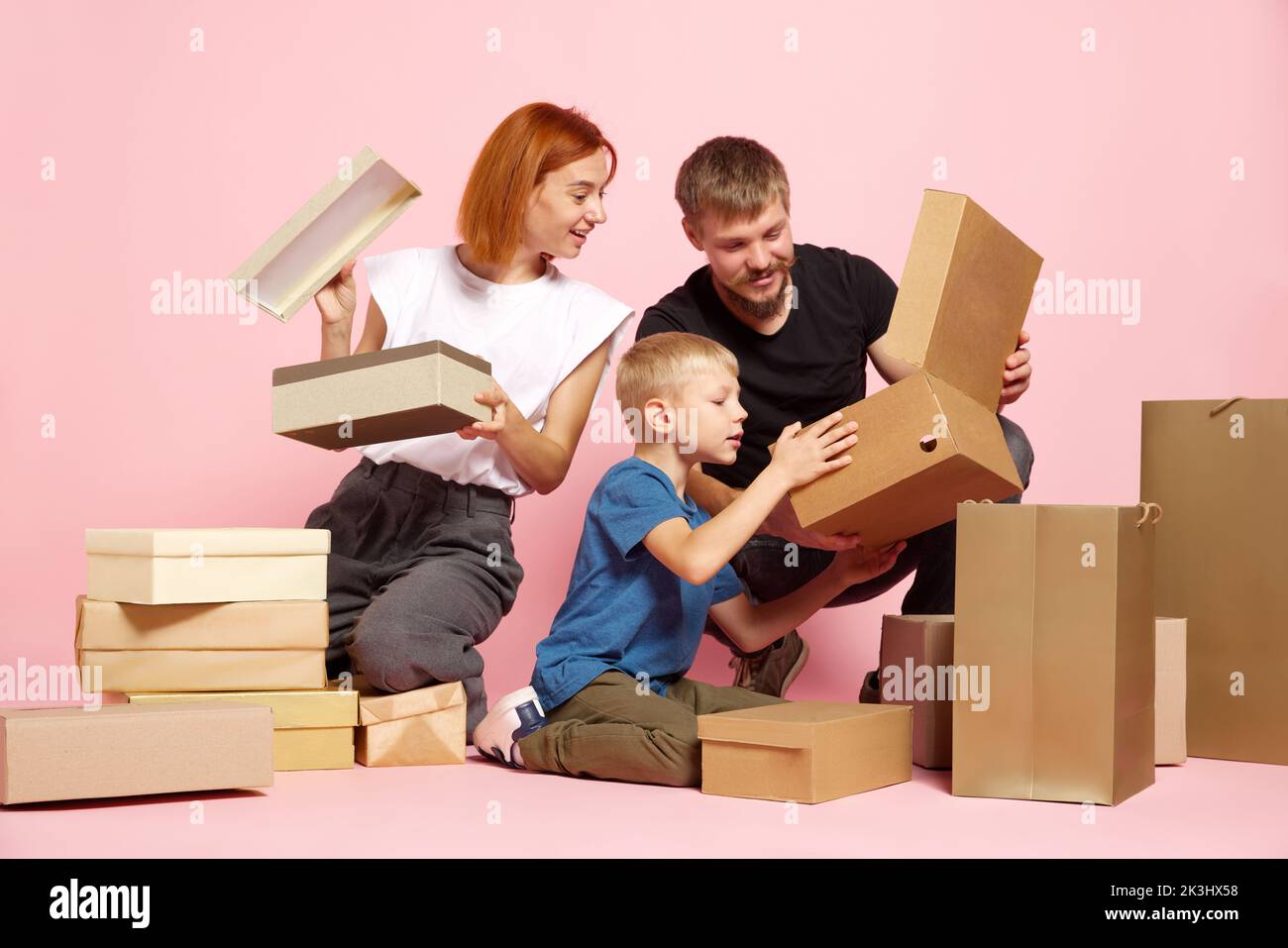 Unpacking. Happy mother, father and son open cardboard boxes, receive ...