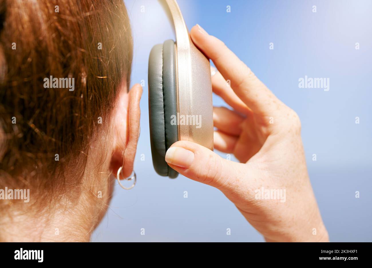 Hands of woman with headphones listening to music for peace of mind, freedom and relax outdoor back view. Podcast, radio and calm girl streaming rock Stock Photo