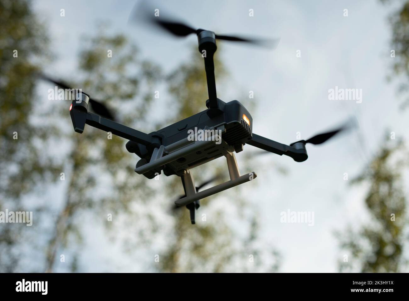 Drone flies low. Drone flight in sky. Technology of flight and shooting from sky. Device with propeller. Combat drone. Stock Photo