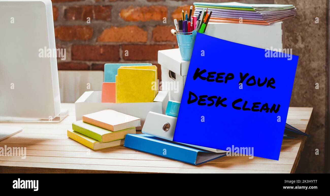 Composite of keep your desk clean on sticky note with office supplies and desktop on table Stock Photo