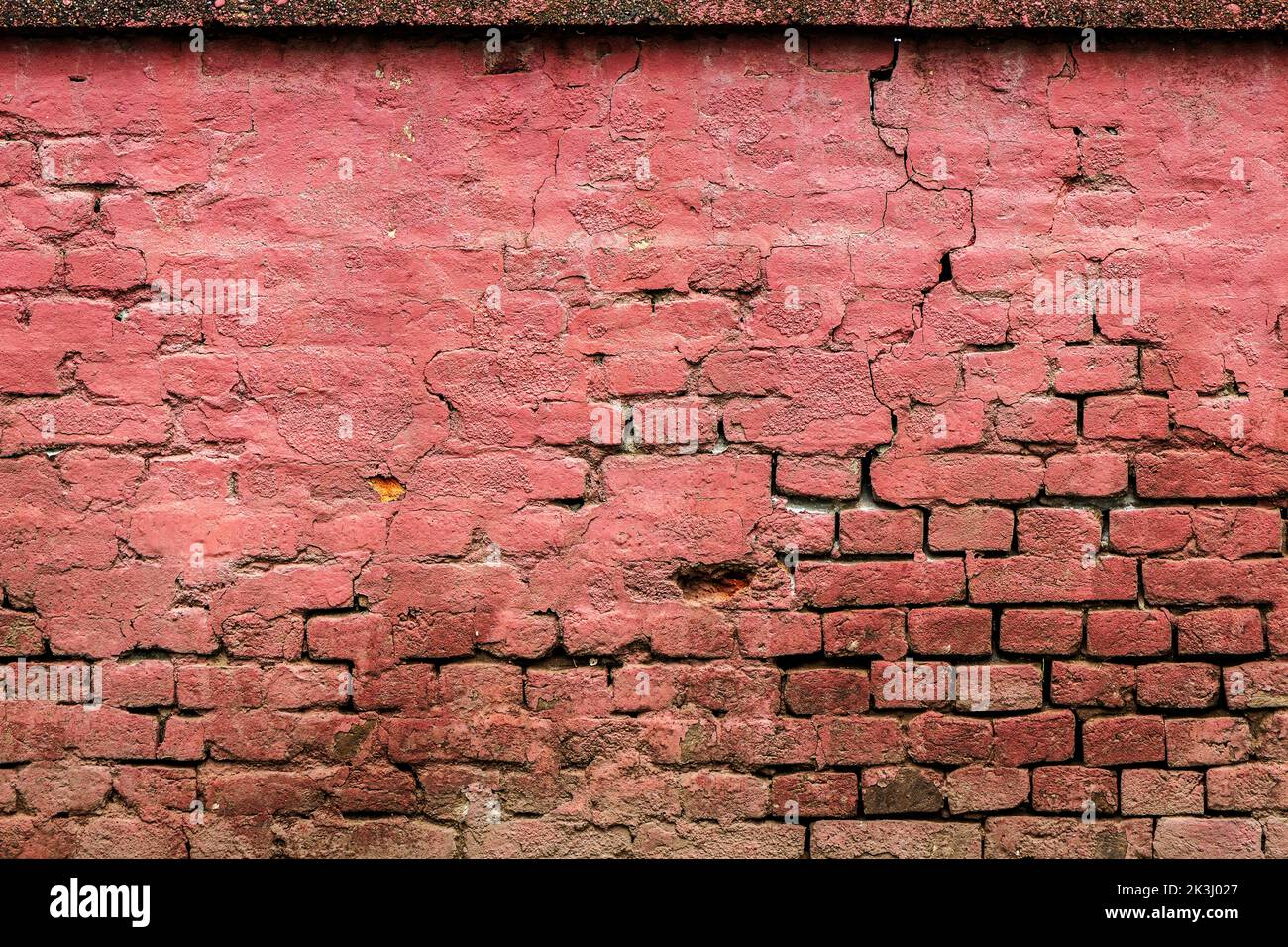 Texture of an old weathered damaged brick wall as background, ruined house facade pattern Stock Photo