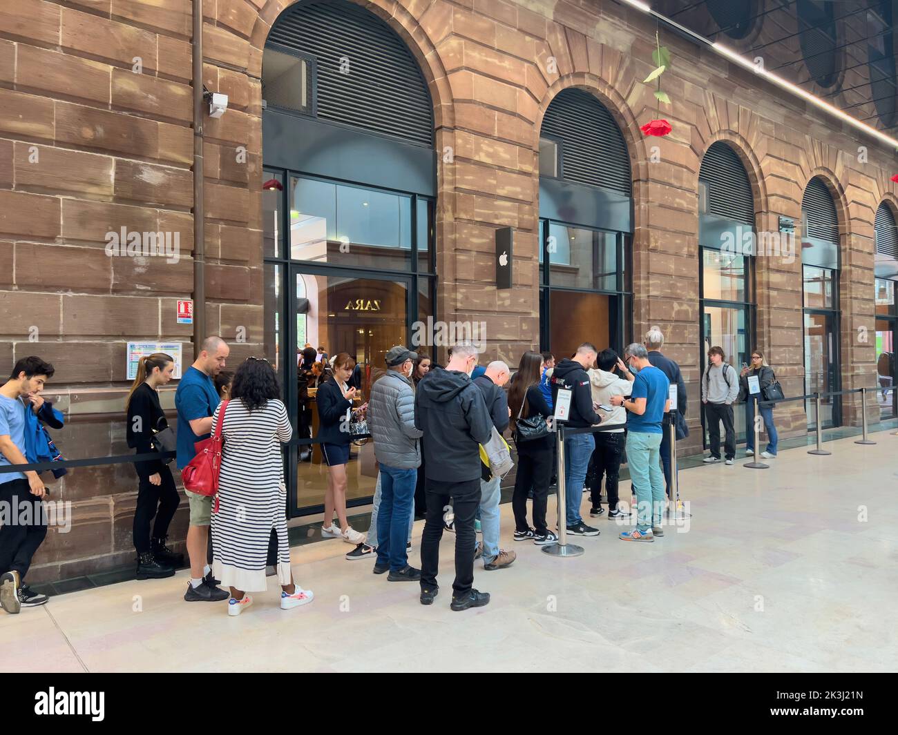Paris, France - Sep 16, 2022: Group of adult and young people in line queue in front of Apple Store with customers waiting in line to buy the latest iPhone 14 Pro Max Plus smartphone, Apple Watch series 8 and Ultra Stock Photo
