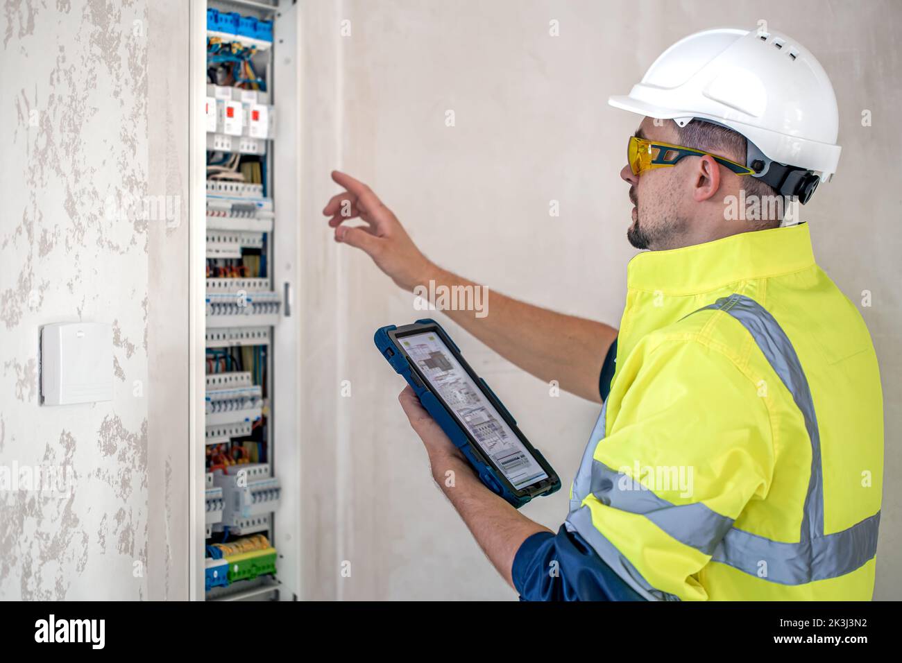 Electrical technician looking focused while working in a switchboard with fuses. Stock Photo
