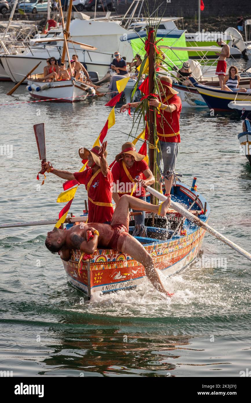 The annual festival of 'U Pisci a Mari' in the Sicilian village of Aci Trezza, near Catania. This takes place around the Feast of the Nativity of St John the Baptist, at the end of June. It represents a traditional fishing expedition for swordfish, which used to take place in the Strait of Messina. The part of the swordfish is played by a swimmer, who is repeatedly caught by the fishermen, bloodily sliced up but then somehow manages to escape. Eventually the 'swordfish' manages to overturn the boat. (Cutting up the 'swordfish') Stock Photo