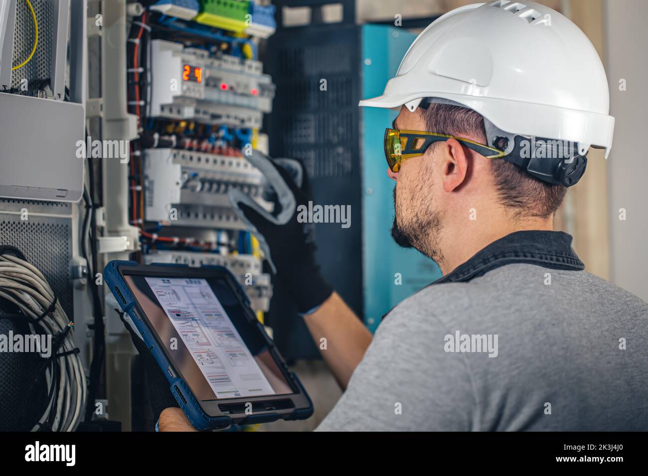 Man, an electrical technician working in a switchboard with fuses. Stock Photo