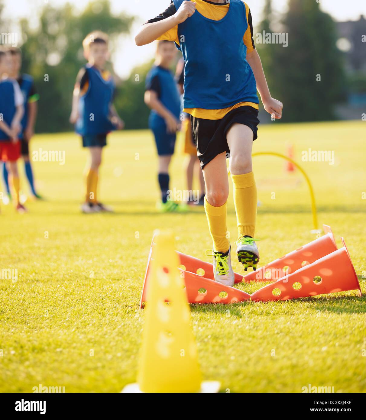School Boy Running Slalom Track Between Training Poles and Jumping Over