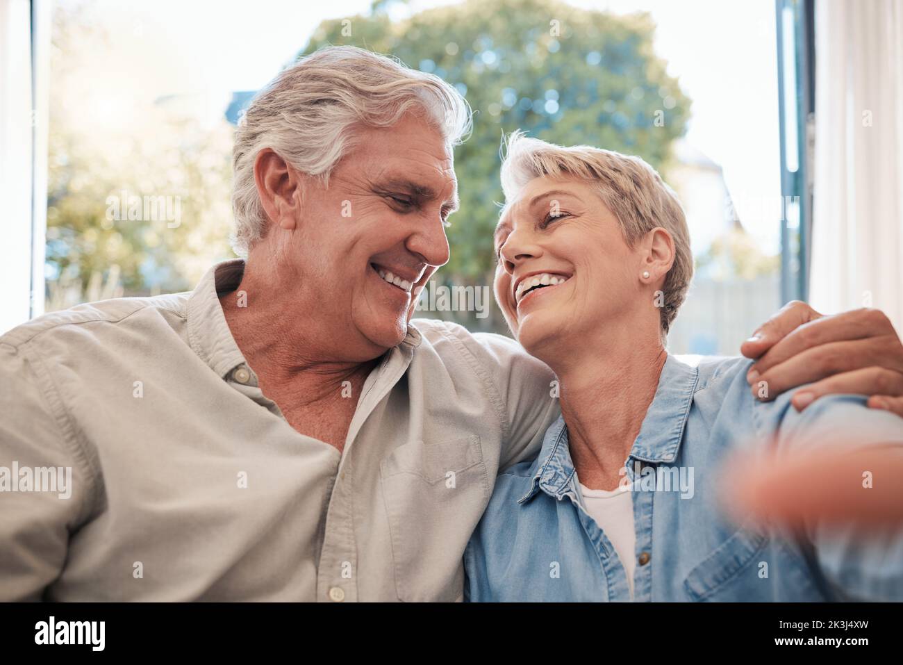 Love, elderly and selfie with retirement couple in home relaxing with romantic eye contact. Married and happy pension people in relationship with care Stock Photo
