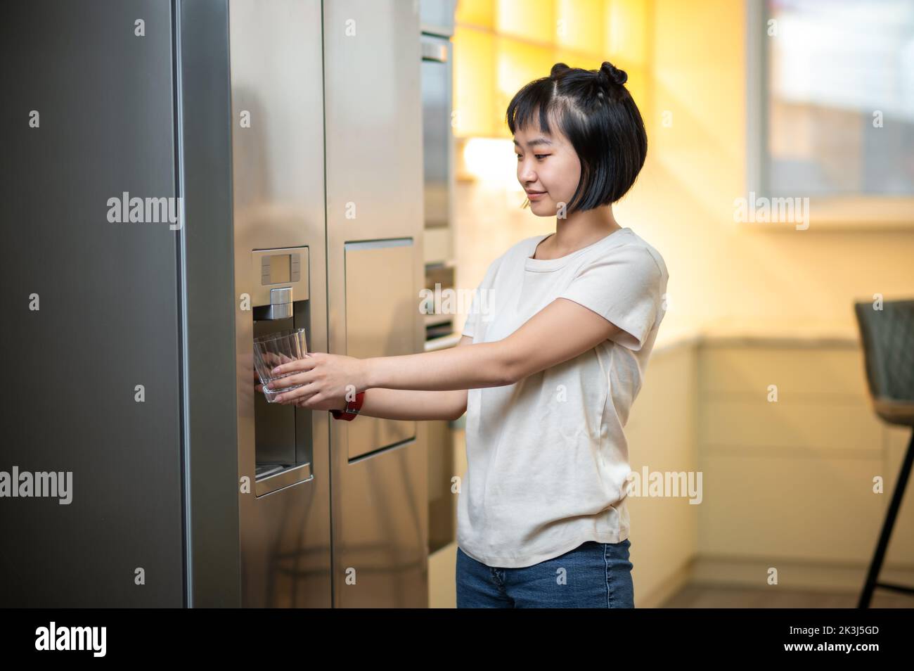 Young female using the refrigerator water dispenser Stock Photo Alamy