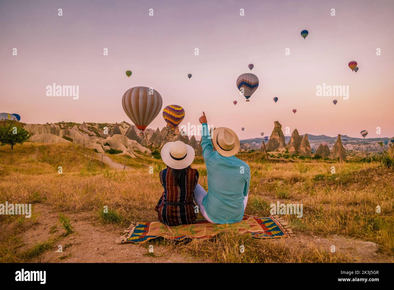 Kapadokya Cappadocia Turkey, a happy young couple during sunrise watching the hot air balloons of Kapadokya Cappadocia Turkey during vacation. Asian women and caucasian men on holiday in Turkey Stock Photo