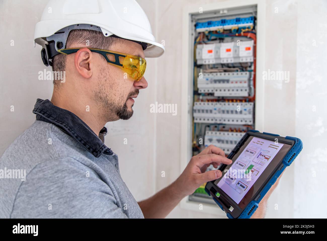 Electrical technician looking focused while working in a switchboard with fuses. Stock Photo