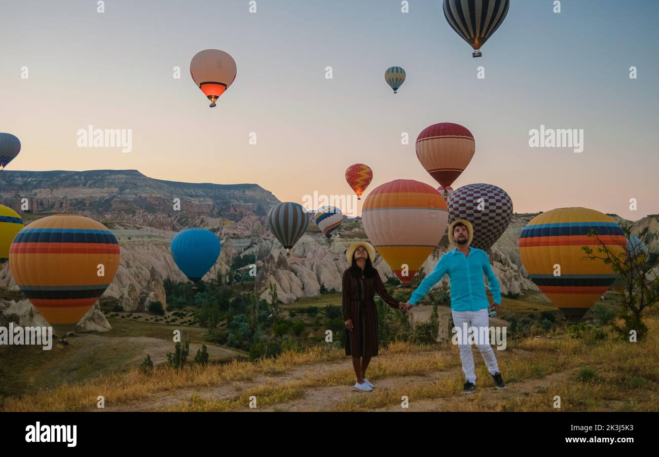 Asian women and caucasian men mid age on a trip to Kapadokya Cappadocia Turkey, a happy young couple during sunrise watching the hot air balloons of Kapadokya Cappadocia Turkey during vacation Stock Photo