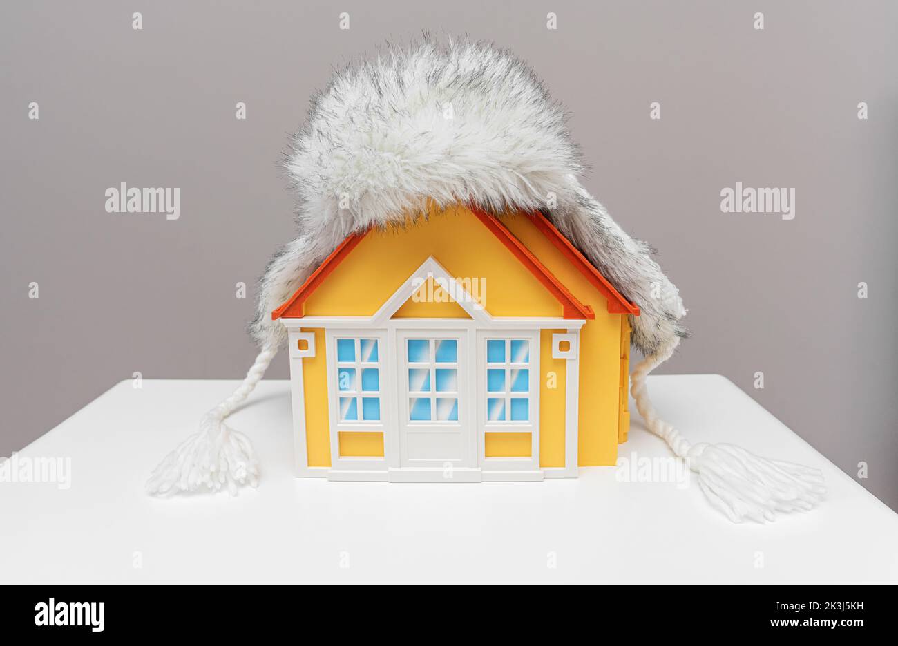 Warm hat with earflaps on the roof of the house. Stock Photo