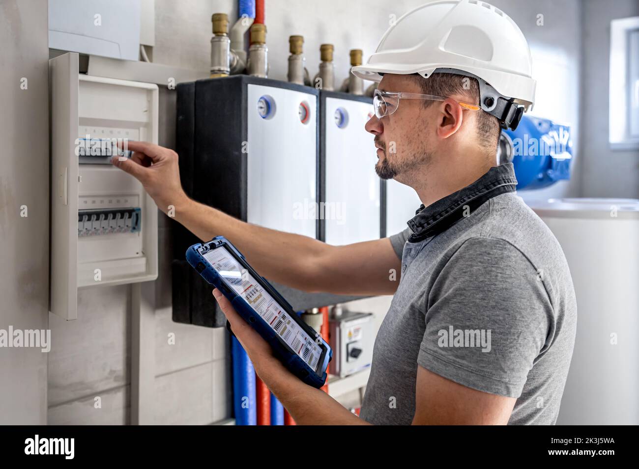 Electrical technician looking focused while working in a switchboard with fuses. Stock Photo