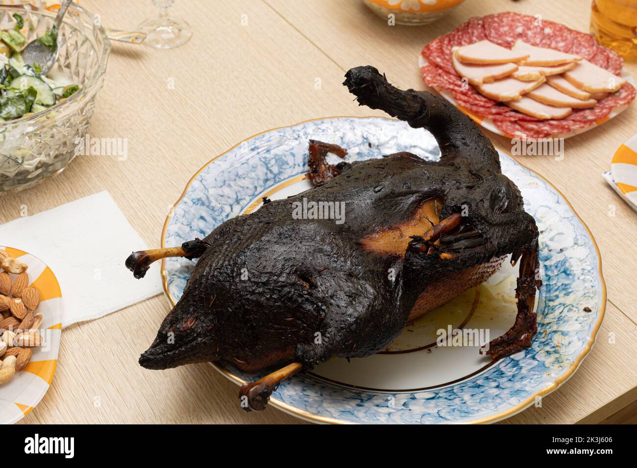 Burnt bird carcass on serving plate on dining table. Serve charred spoiled dish. Lousy housewife and bad chef. Delicious cold starters and terrible Stock Photo