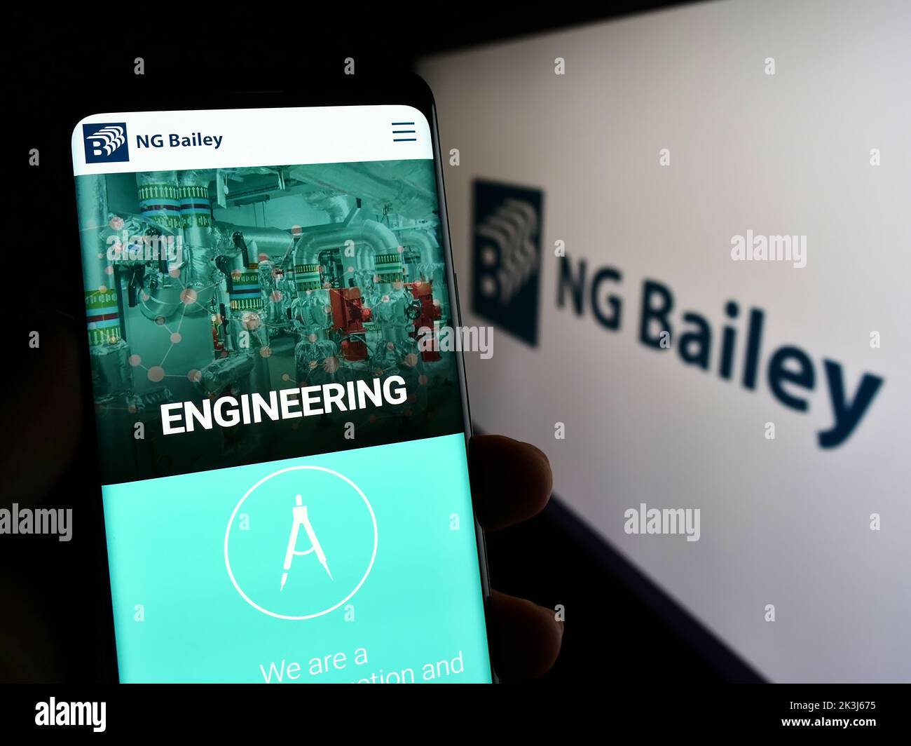 Person holding cellphone with webpage of engineering company NG Bailey Group Limited on screen in front of logo. Focus on center of phone display. Stock Photo