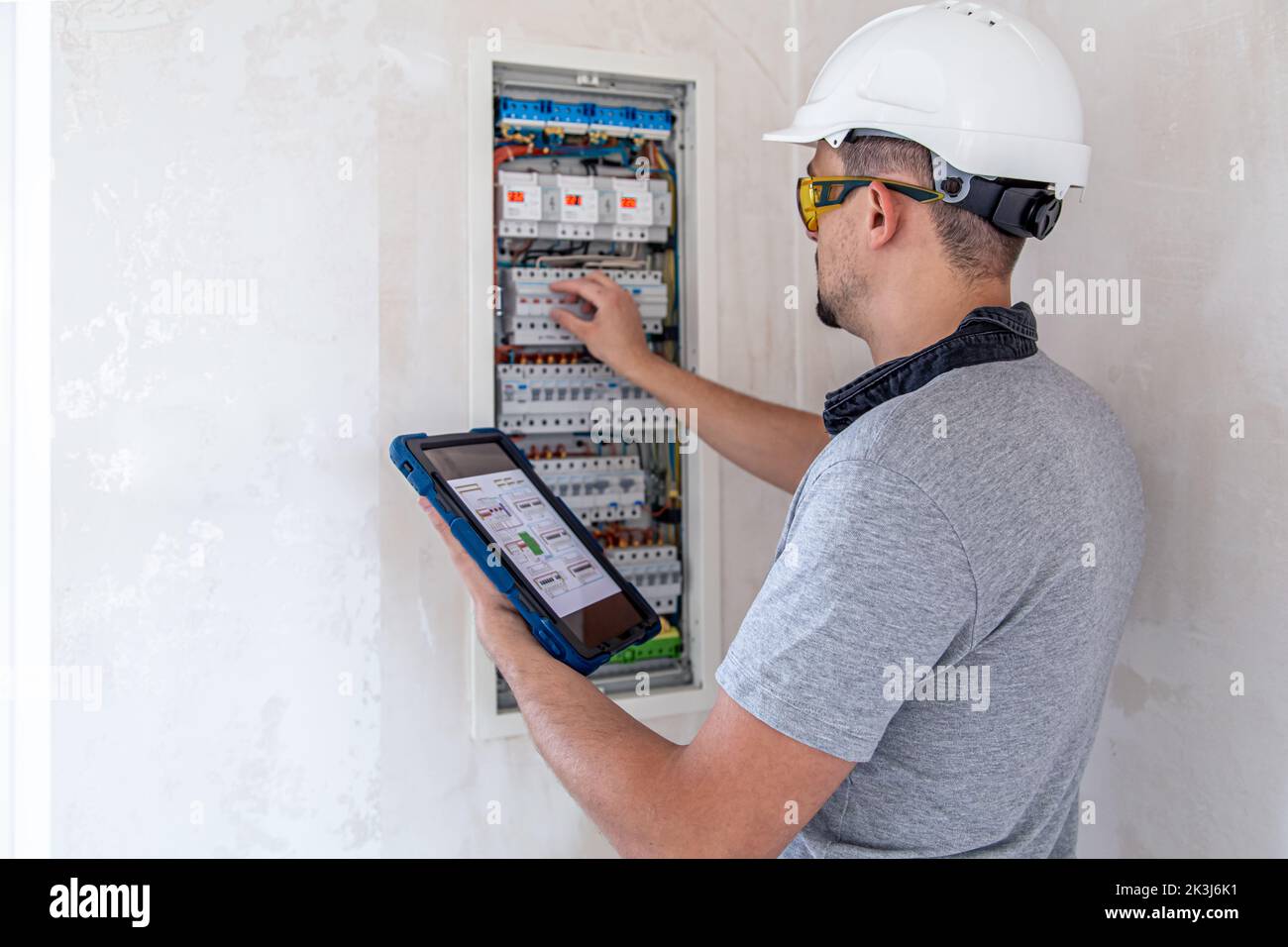 Electrical technician looking focused while working in a switchboard with fuses. Stock Photo