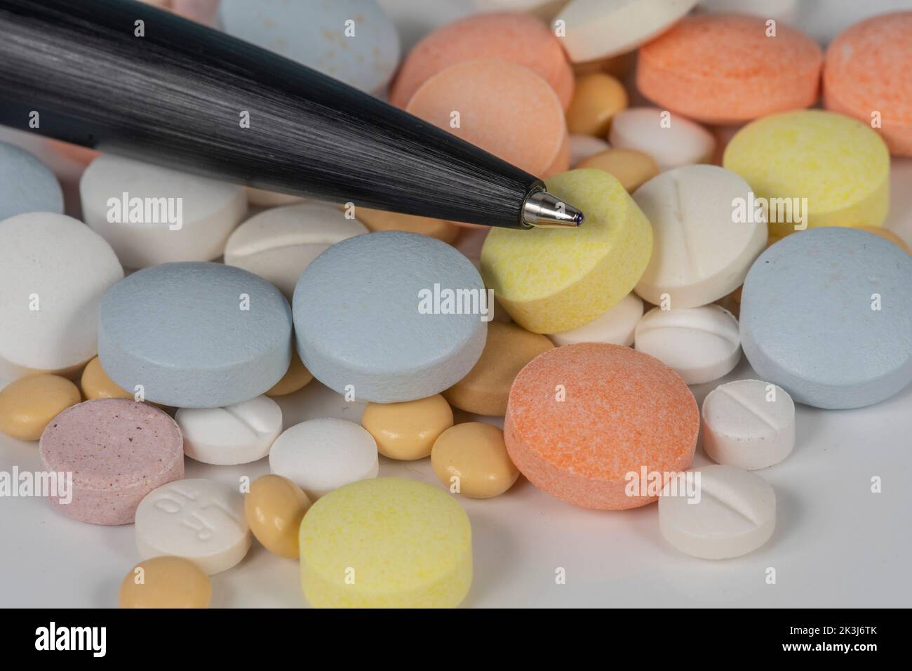 Medicines (tablets, capsules, pills) of different sizes and colors, stacked in bulk. Illness