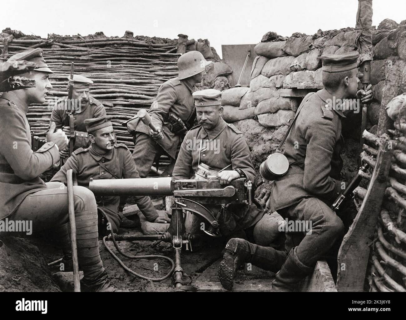 Six German soldiers with a Maschinengewehr 08, or MG 08 machine gun, capable of firing 450-500 rounds a minute, and a mere 40 meters from the British line.  The soldier at right, with gas mask canister slung over his shoulder, is peering into a periscope to get a view of enemy activity. The soldier at rear, with steel helmet, holds a “potato masher” model 24 grenade. Stock Photo