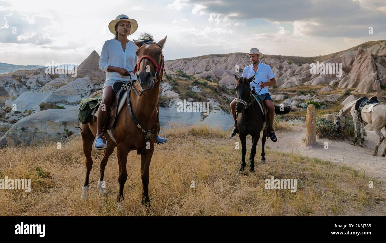 happy young couple on vacation in Turkey Kapadokya horse riding in the mountains in the background of Cappadocia Goreme. Horse riding in Cappadocia Stock Photo