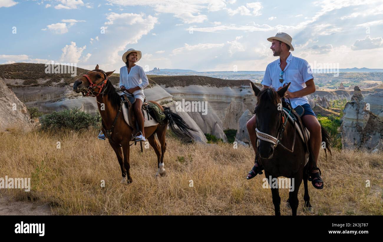 happy young couple on vacation in Turkey Kapadokya horse riding in the mountains in the background of Cappadocia Goreme. Horse riding in Cappadocia Stock Photo