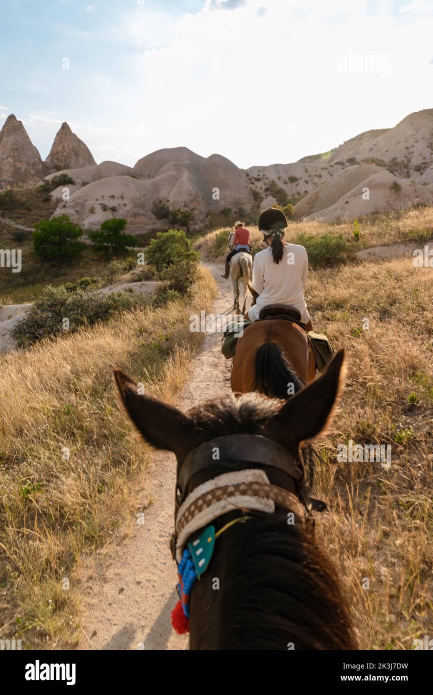 young woman during a vacation in Turkey Kapadokya watching the hot air balloons of Cappadocia. Asian women on the back of a brown horse in the valley of Cappadocia Stock Photo