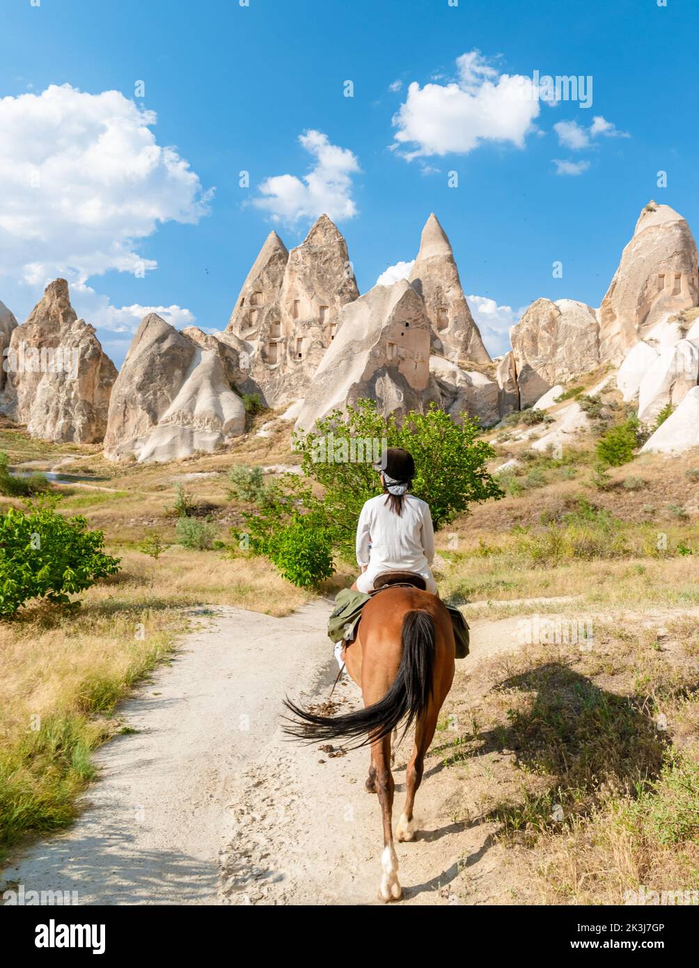 young woman during a vacation in Turkey Kapadokya watching the hot air balloons of Cappadocia. Asian women on the back of a brown horse in the valley of Cappadocia Stock Photo