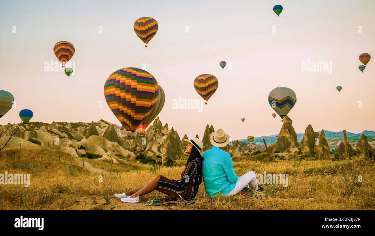 Asian women and caucasian men mid age on a trip to Kapadokya Cappadocia Turkey, a happy young couple during sunrise watching the hot air balloons of Kapadokya Cappadocia Turkey during vacation Stock Photo