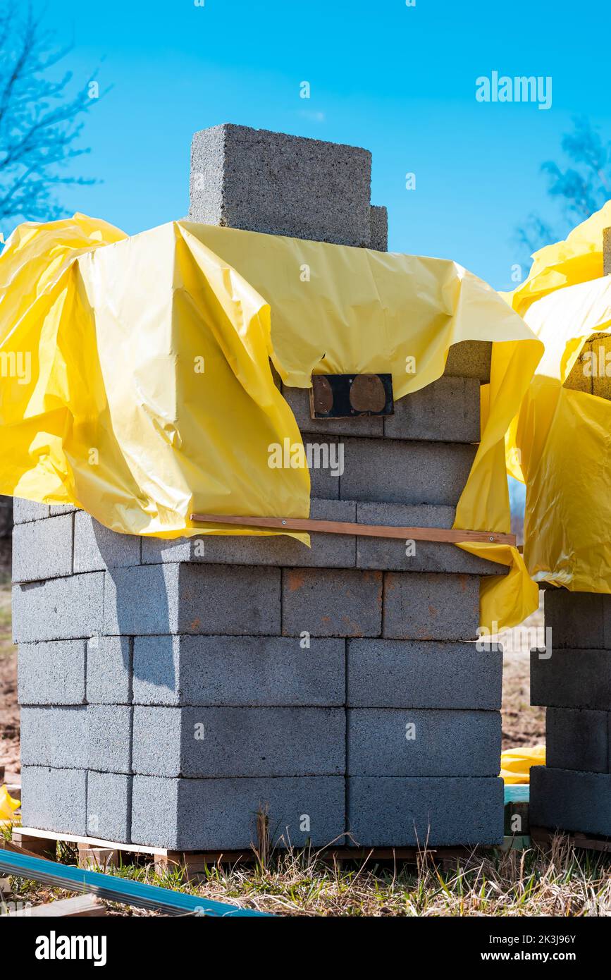 A vertical shot of a stack of gray bricks near a construction site ...