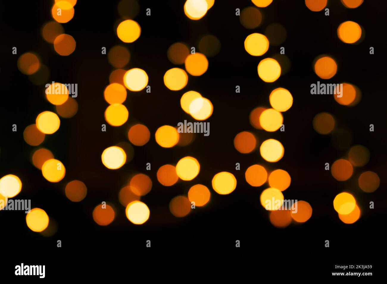 abstract holiday background: yellow bokeh lights in darkness Stock Photo