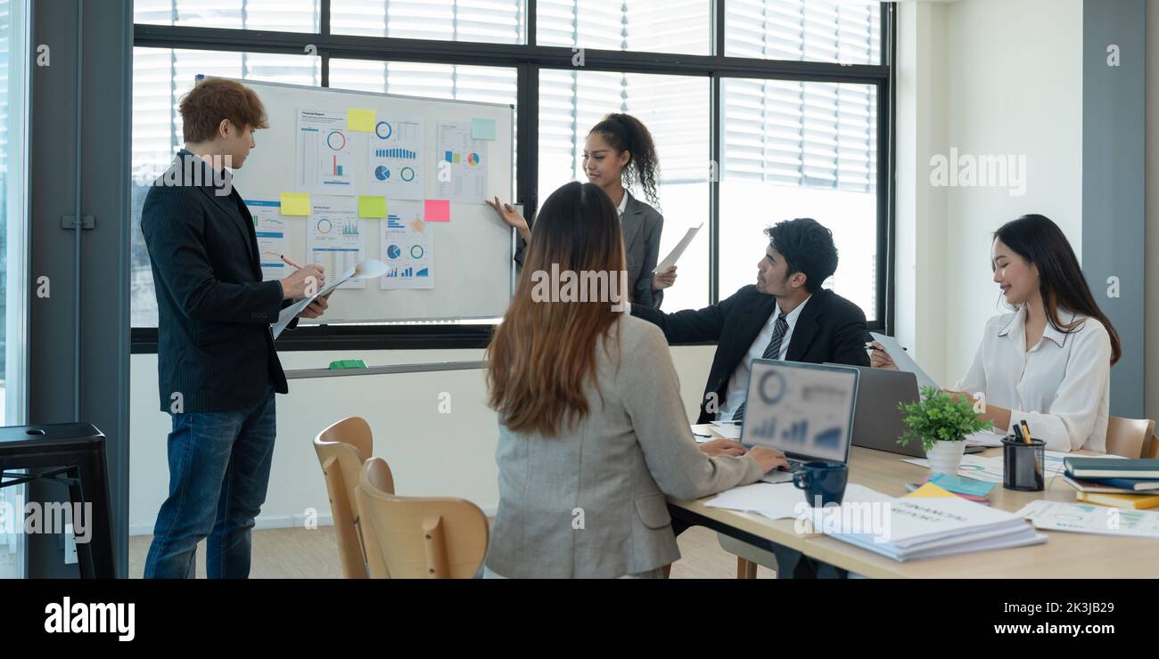 Group of diverse colleagues discussing for financial report with presentation on flipchart during a small conference in the office Stock Photo