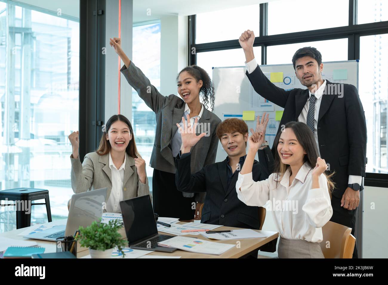 Business people smile and raise hands up, feeling happy, complete finish job, teamwork successful achievement working in office concept Stock Photo