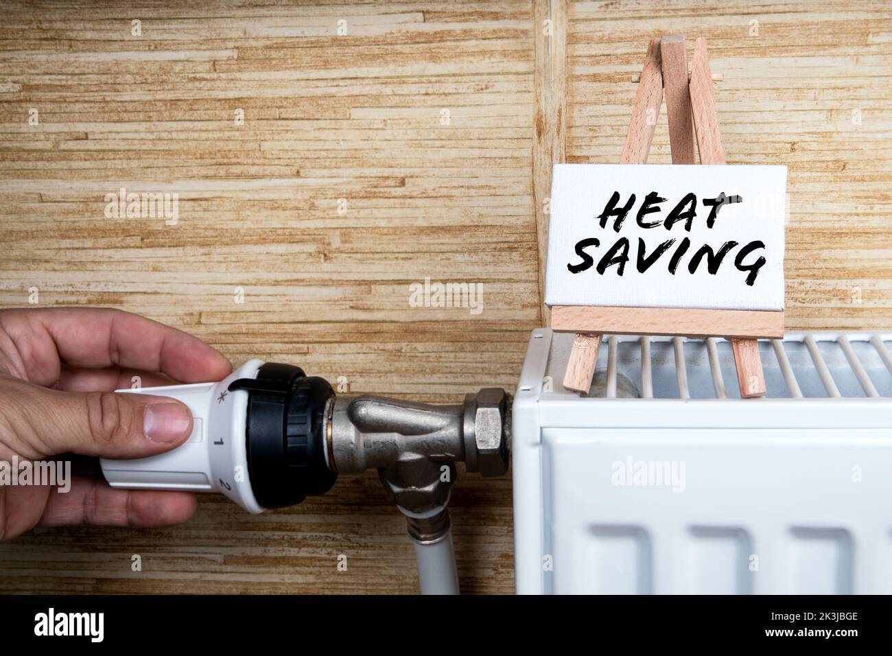 Heat Saving. Turning down thermostat on radiator to save energy. Stock Photo