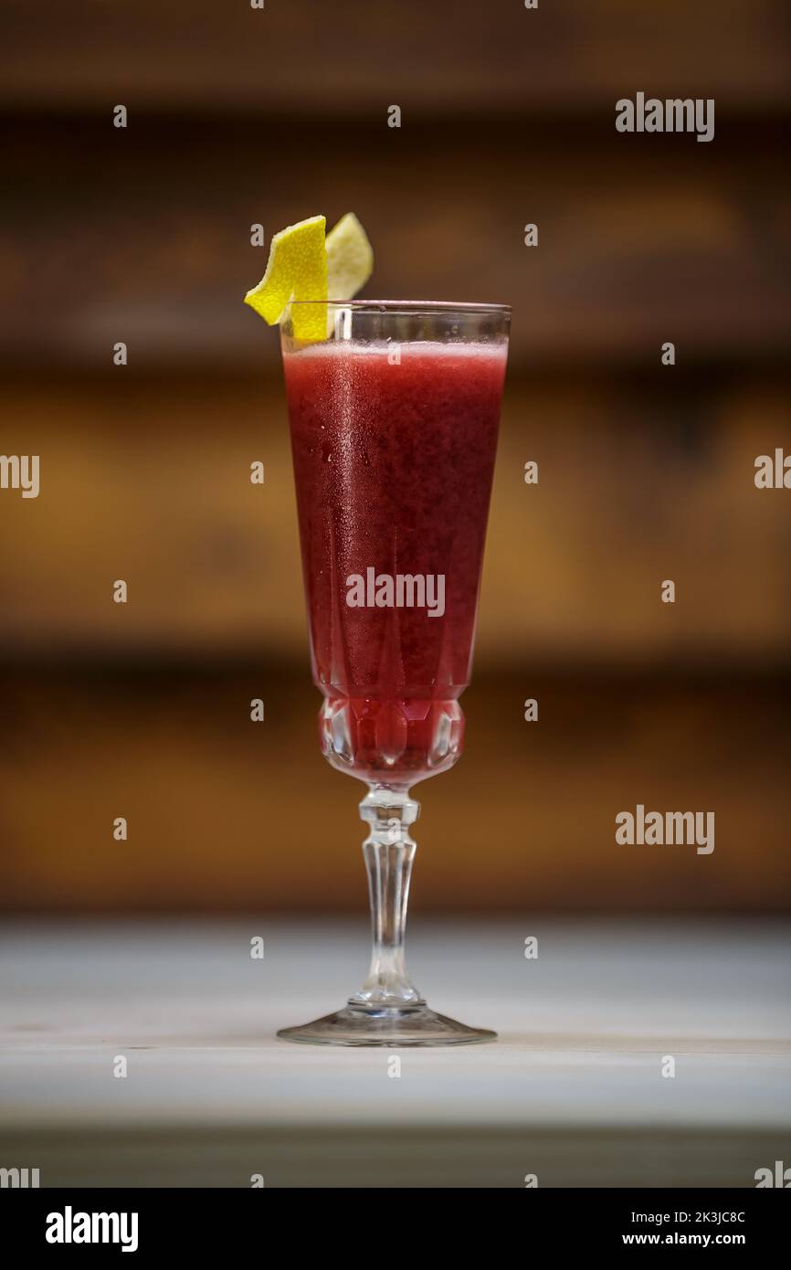 Red cocktail in a tall glass with a lemon twist, wooden background Stock Photo