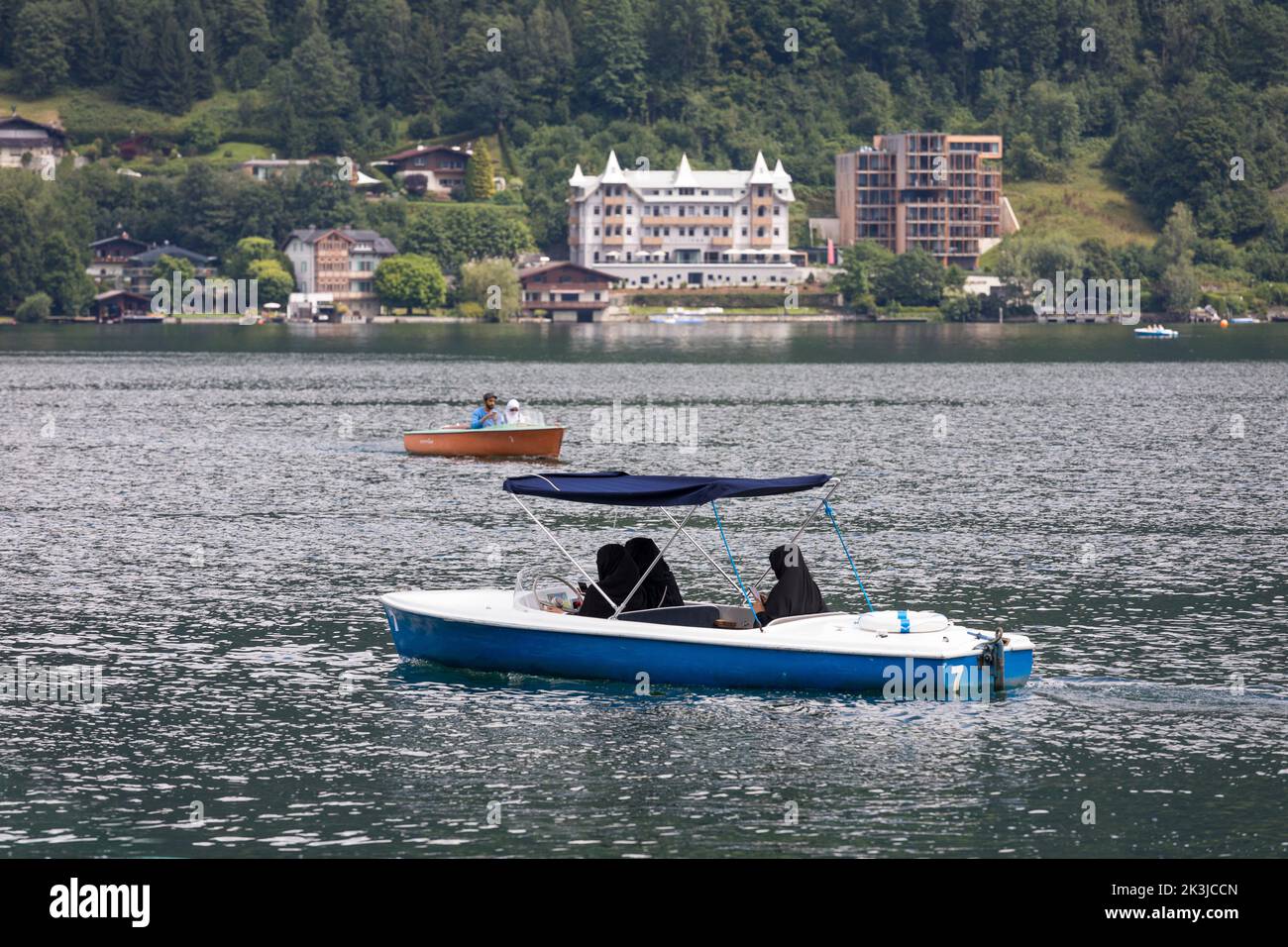 Arab women in black burqa dresses sailing a rent motorboat in Zell am See, Austria Stock Photo