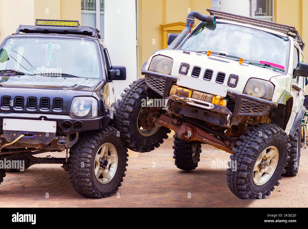 Suzuki Jimny mini SUV car,Tomsk Russia September 10, 2022.An upgrade for better cross-country ability by craftsmen.SUV drove onto wheel of another SUV Stock Photo