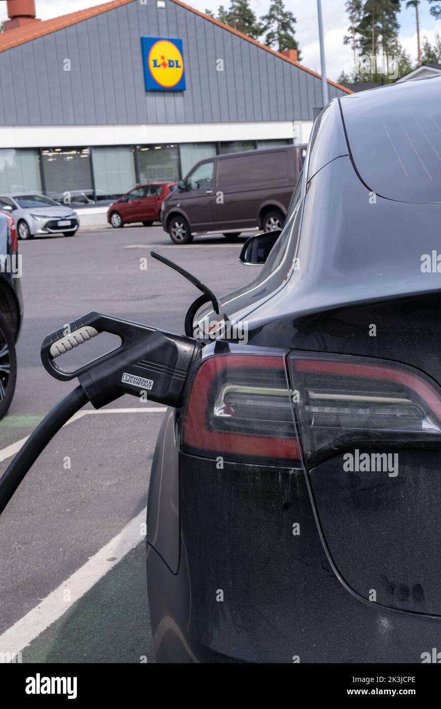 Jarvenpaa, Finland - August 11, 2022: A static shot of a solid black Tesla Model 3 dual motor charging at the Lidl supermarket DC charging station in Stock Photo