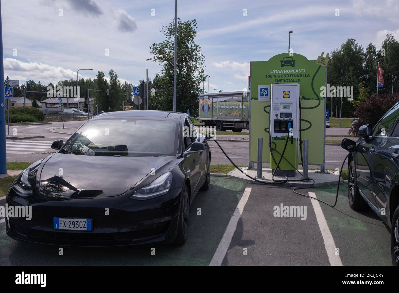 Jarvenpaa, Finland - August 11, 2022: A static shot of a solid black Tesla Model 3 dual motor charging at the Lidl supermarket DC charging station in Stock Photo