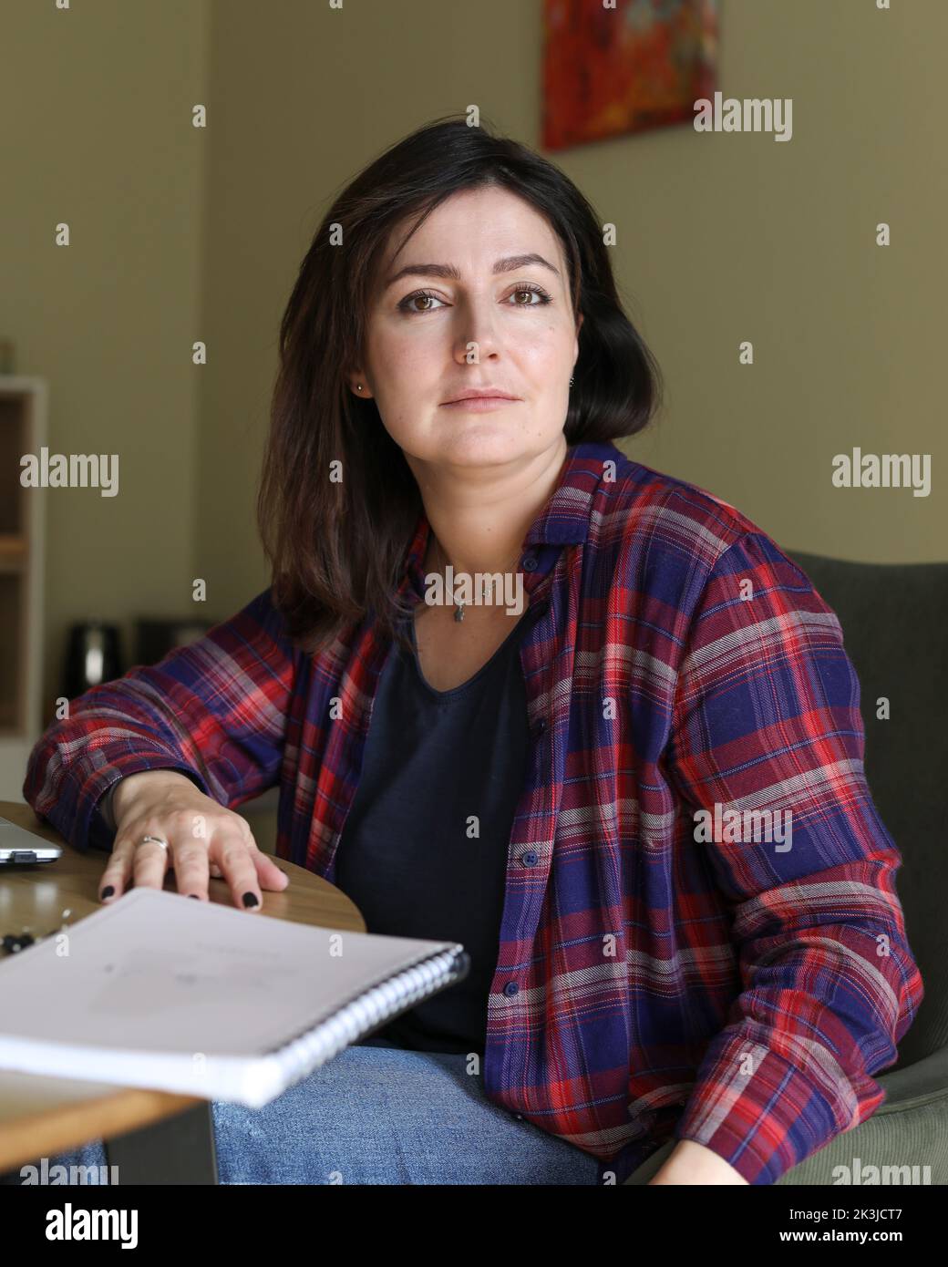 Vertical confident, powerful smiling dark-haired woman looking at camera, sit at office desk with paper report documents Stock Photo