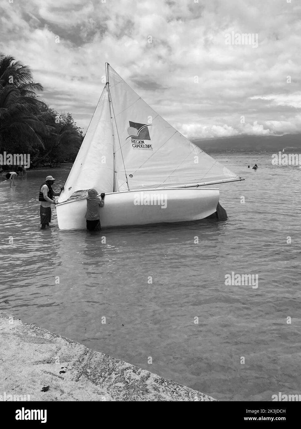 A vertical grayscale shot of a boat moored on the dock of Guadeloupe ...