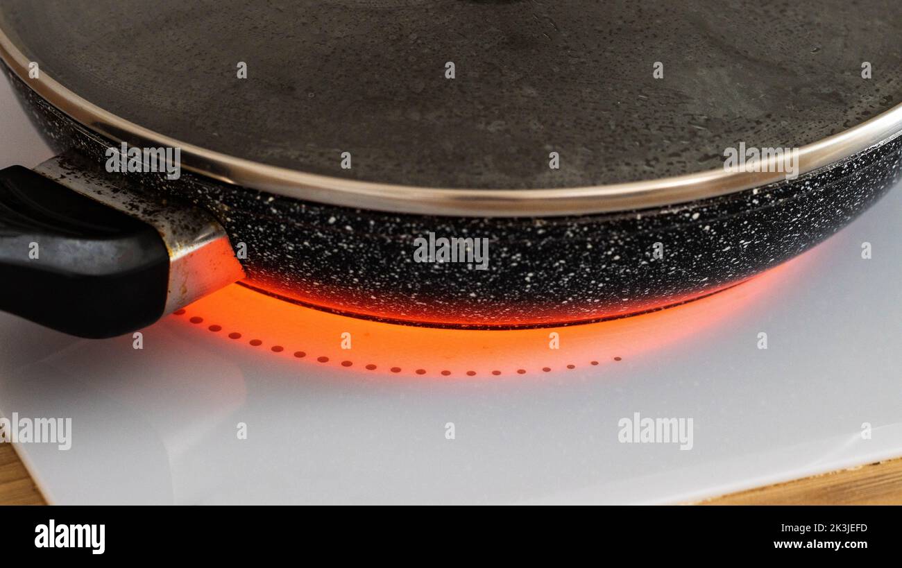 Cooking food in a frying pan on an induction hob, closeup. Modern