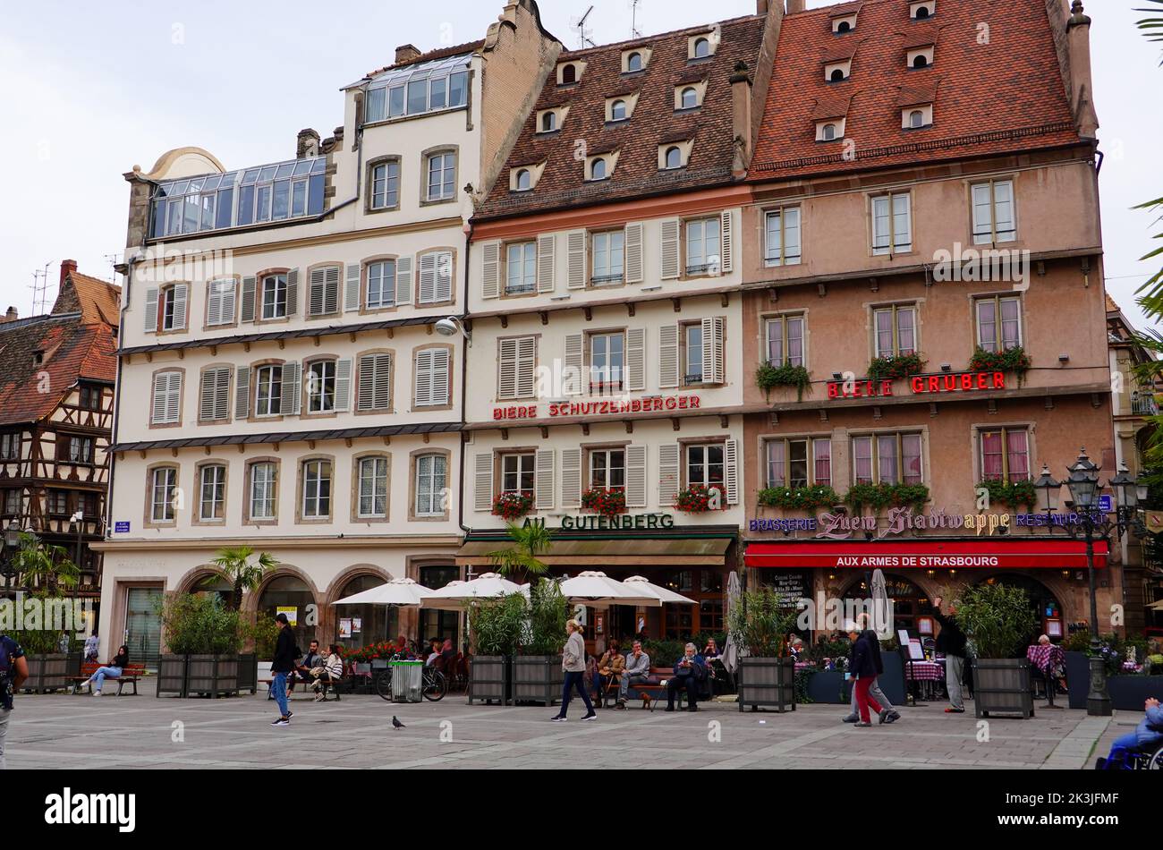 People sitting, walking, in front of buildings with architecture distinctive of the Alsace region, Place Gutenberg, Strasbourg, France. Stock Photo