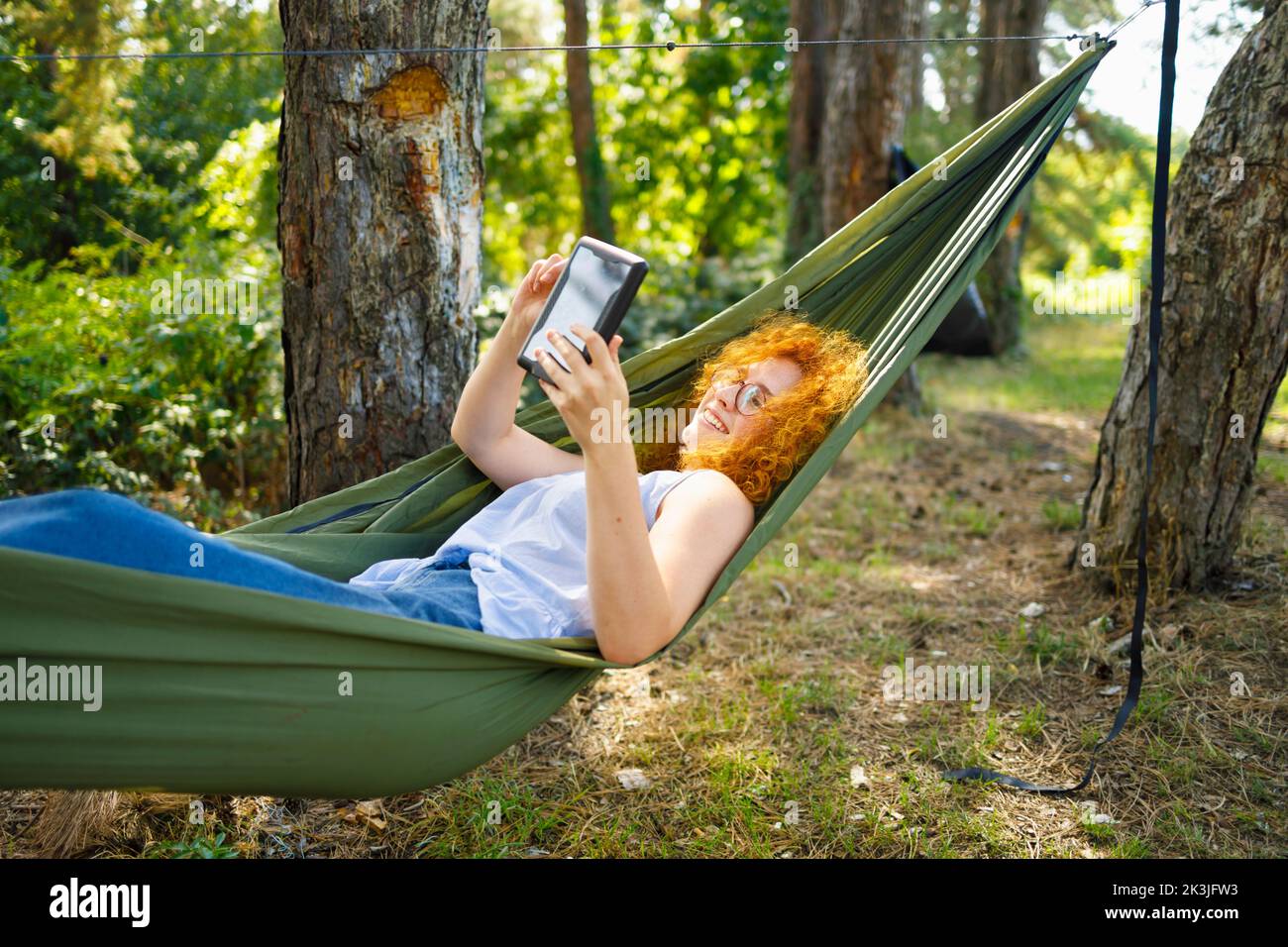 A woman laying in a hammock and buying online with her tablet Stock Photo