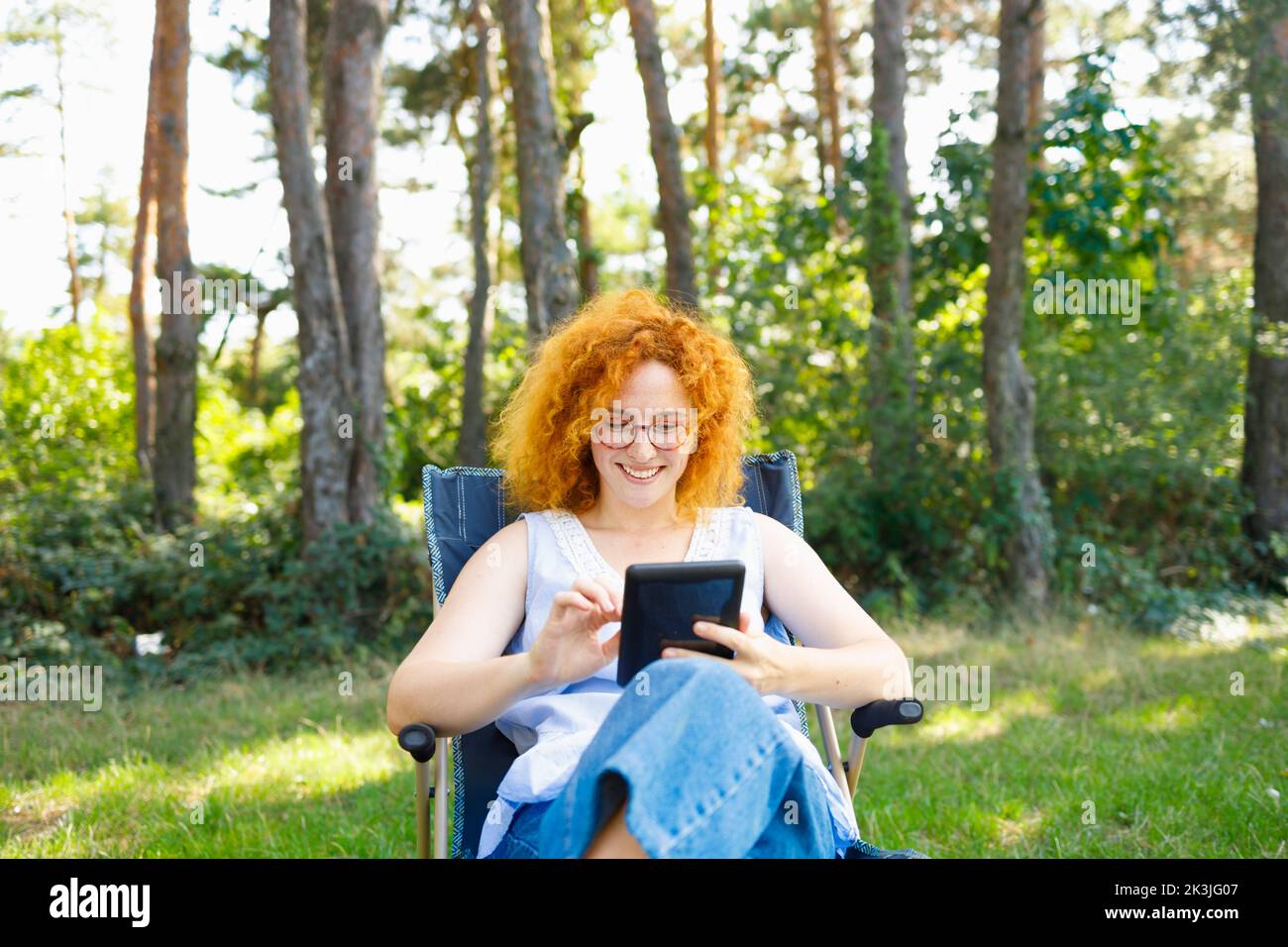 A woman sitting in nature and browsing internet and purchasing for the Black Friday Stock Photo