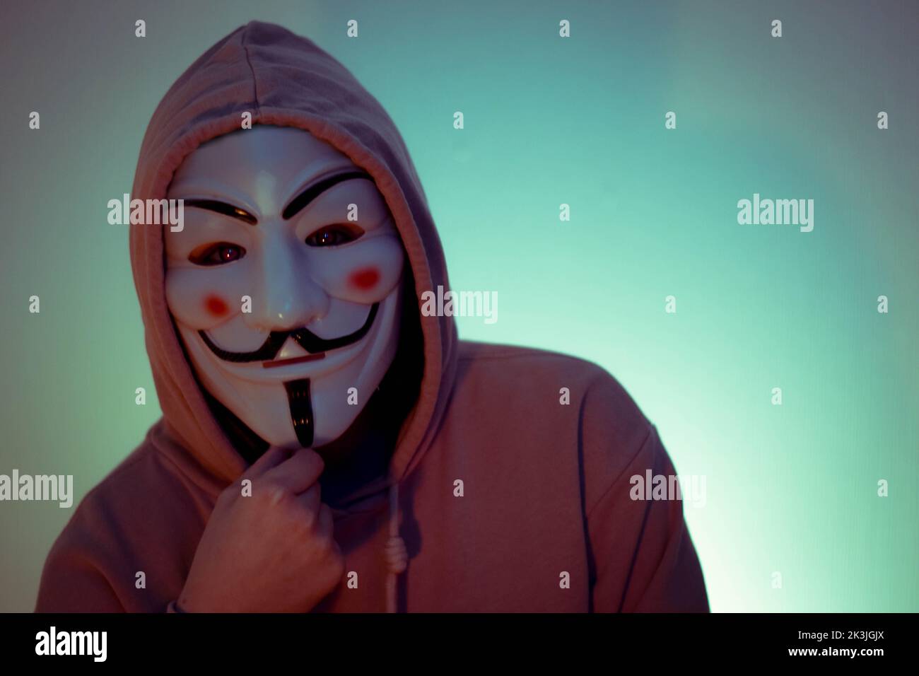 A portrait of a person wearing a hoodie and the Guy Fawkes mask Stock Photo