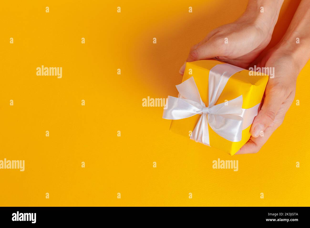 Woman holding gift box on color background Stock Photo - Alamy