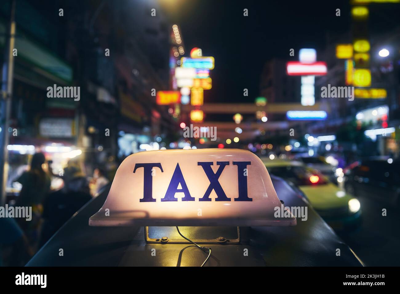 Illuminated taxi sign on roof of tuk tuk. Night traffic in Chinatown in Bangkok, Thailand, Stock Photo