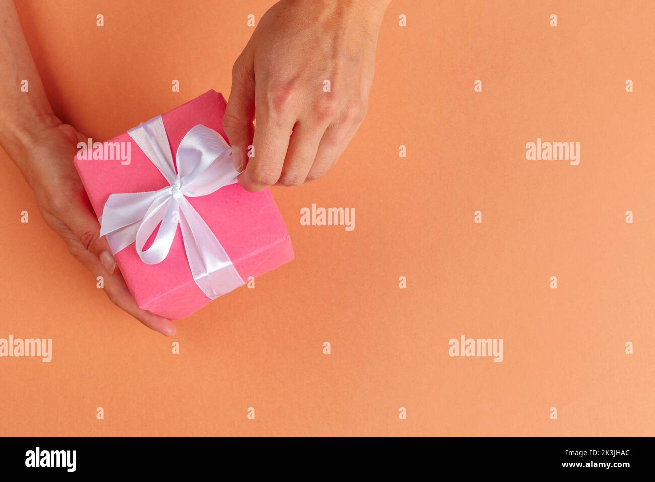 Woman holding gift box on color background Stock Photo - Alamy