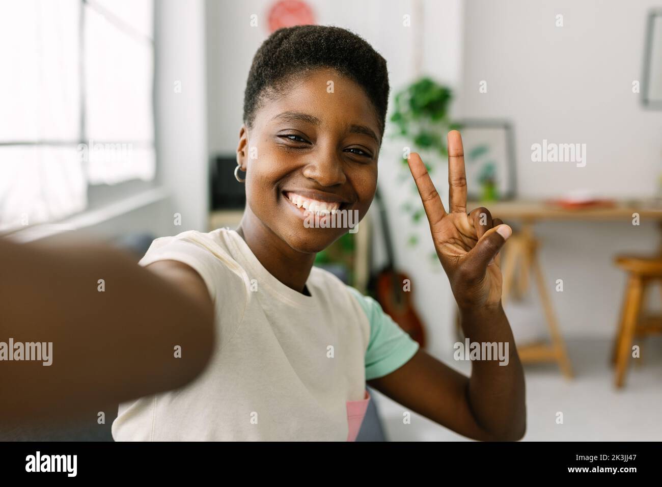 Cheerful young african woman taking selfie portrait with phone at home office Stock Photo
