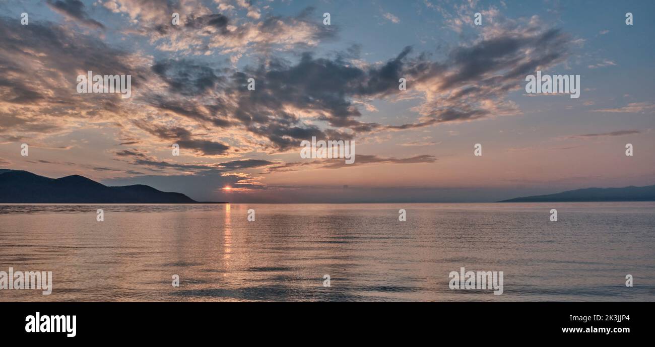 Colorful summer sunset on lake. Scenic dramatic clouds on sky. Stock Photo